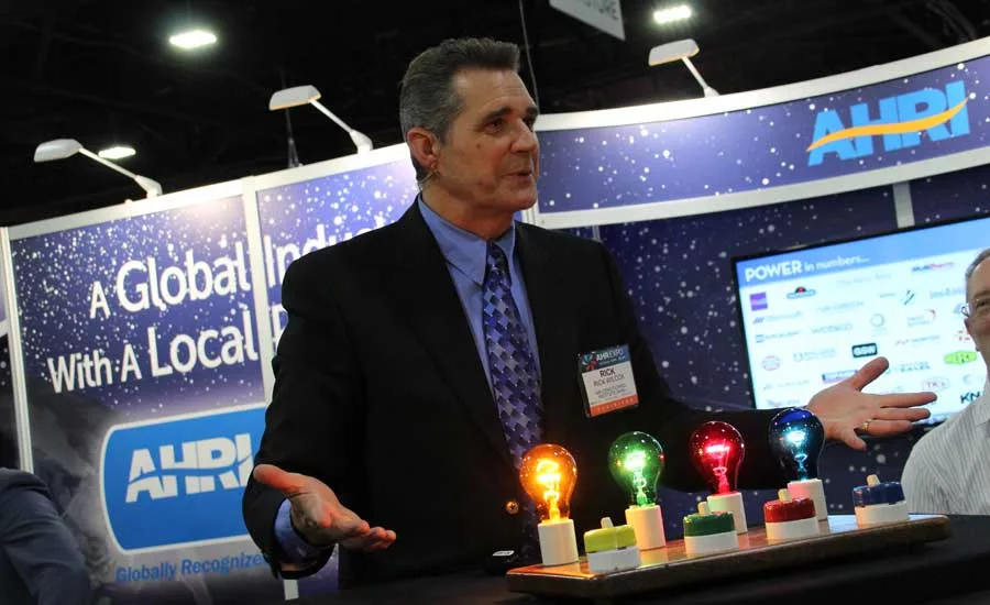 Rick Wilcox performs magic and card tricks for a crowd at the Air-Conditioning, Heating, and Refrigeration Institute (AHRI) booth. - The ACHR News