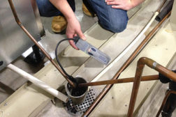 A service technician can use an electronic leak detector in the water drain area for the water-cooled condenser.