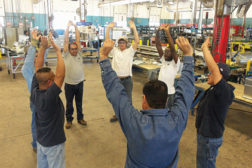 Workers at TDIndustries stretch before the workday as part of a large wellness program put in place by the company.