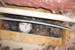 This discolored fiberglass insulation around a can light in an attic is a clue that air movement has been taking place. The insulation acts as a filter as air moves through it.