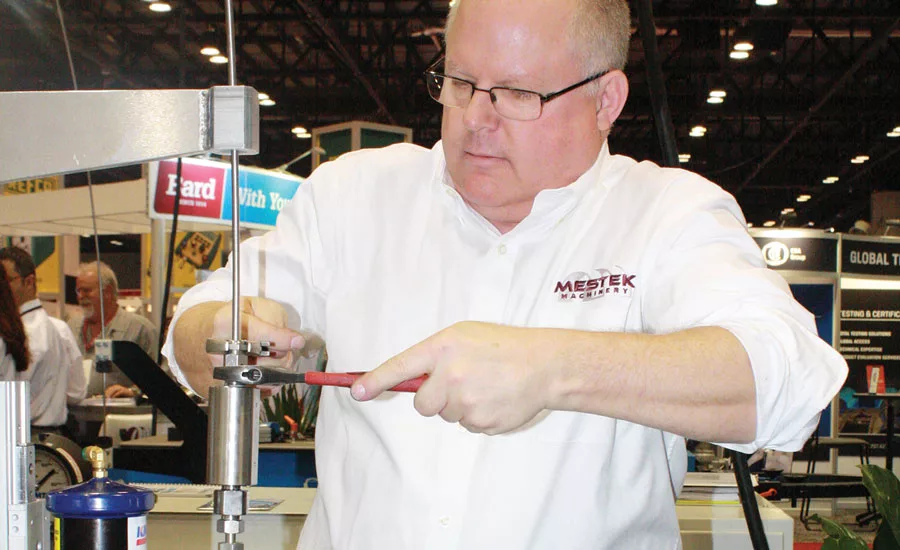 Bill Jilovec, service engineer, Mestek Machinery in Cedar Rapids, Iowa, tightens  a nut during a demonstration at the company’s booth.