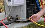 A technician adds a refrigerant sealant to the suction side of a residential air conditioning unit. Photo courtesy of Nu-Calgon