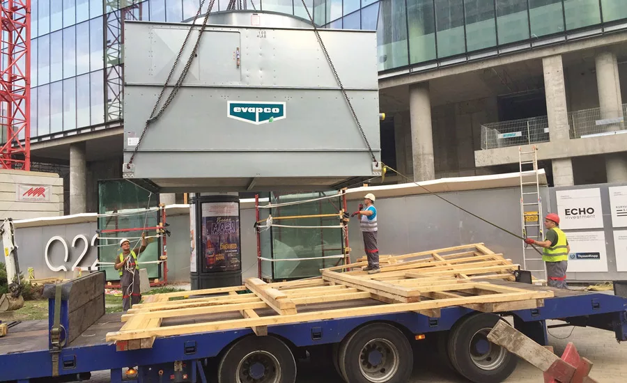 Construction crews rig the top section of an ATWB closed-circuit cooler to be lifted into position atop a tall city structure in Warsaw, Poland. Photo courtesy of Evapco Inc.