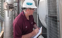 MECHANICAL MAINTENANCE A building engineer examines an LST-style centrifugal cooling tower during a routine maintenance checkup. PHOTO COURTESY OF EVAPCO INC.