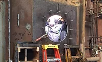 workers weld on a burner plate