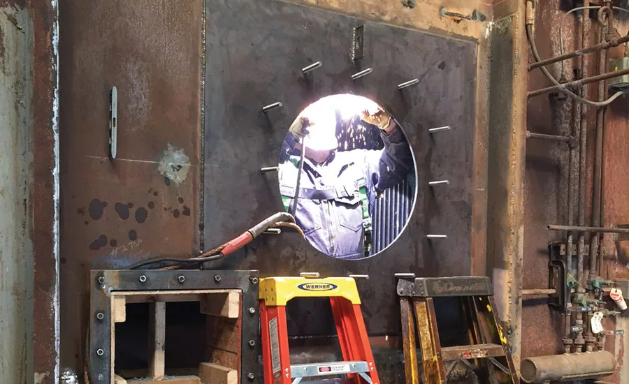 workers weld on a burner plate