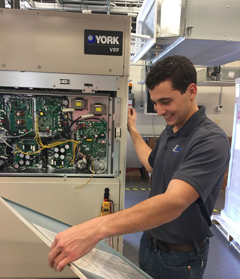 CHECKING OUT: Jared Thompson, assistant project manager at Encore Mechanical, checks out a VRF system. The company has installed many VRF systems in Army facilities since the directive was published. - ACHR