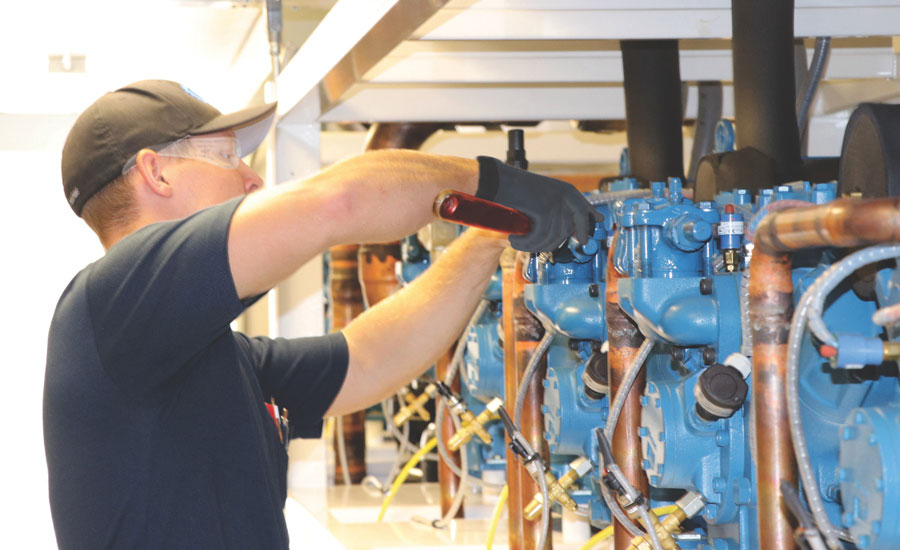 CoolSys is working with many stores that are making the move to low-GWP refrigerants. Here, one of the company’s service technicians works on a refrigeration system. - The ACHR News