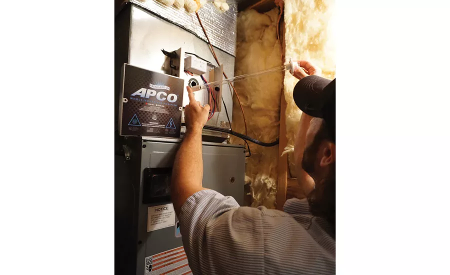 Collin Poyle, a technician at Hagerstown Heating and Cooling, installs a UV lamp. - The ACHR News