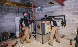 Vertex mechanical technicians move the 4-ton Q Energy ground source heat pump into place during a retrofit. - The ACHR News