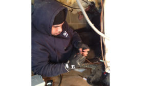 Jose Delgado, a technician with Gaithersburg, Maryland-based GAC Services, works on low-voltage wiring for an air handler inside a customer&rsquo;s crawl space. - The ACHR News