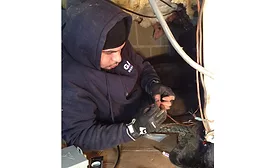 Jose Delgado, a technician with Gaithersburg, Maryland-based GAC Services, works on low-voltage wiring for an air handler inside a customer&rsquo;s crawl space. - The ACHR News