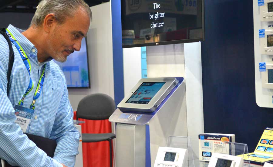 A visitor at the Braeburn booth stops to admire the simplicity of the company’s smart thermostat offerings. - The ACHR News