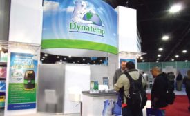 Dynatemp’s Will Gresham (behind counter) talks to several expo attendees about R-421A, which is a long-term replacement refrigerant for R-22. - The ACHR News