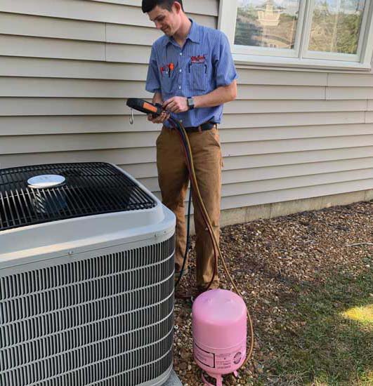 Service technician Garrett Vancil from Welsch Heating and Cooling Co. checks refrigerant levels in a system.