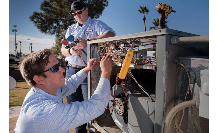 Dan Veatch (in hat), senior HVAC technician, and Jacob Pelto, HVAC service apprentice, from Forrest Anderson Plumbing & Air Conditioning Inc., work on a rooftop unit.