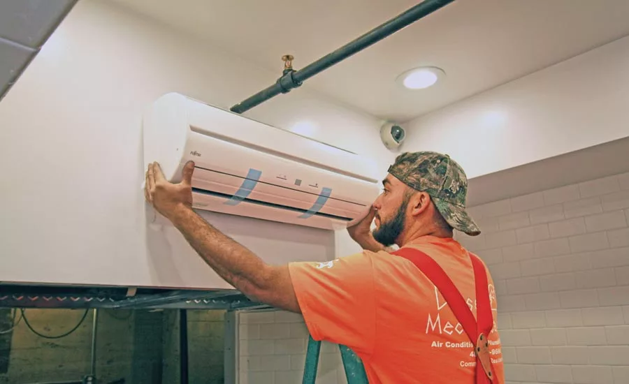 An HVAC tech installs a ductless unit in the ceiling of a Cornish Pasty restaurant.