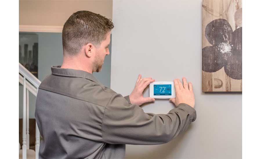 A technician installs a smart thermostat.