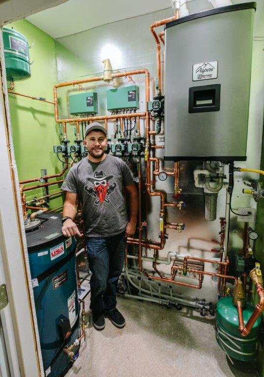 Keefer Rader stands in front of the completed hydronic system.
