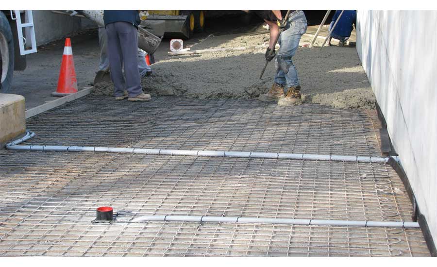 A crew covers a radiant heat system with concrete.
