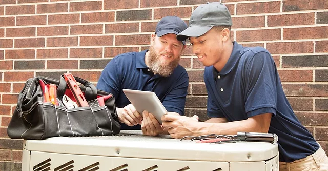 Technicians talk over an outdoor a/c unit