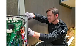 Man installing heat pump outside house