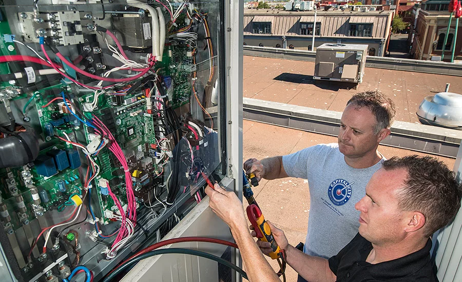 Tim Sykes and Tyler Little, co-founders of Capital City Refrigeration, check connections on a VRF system.