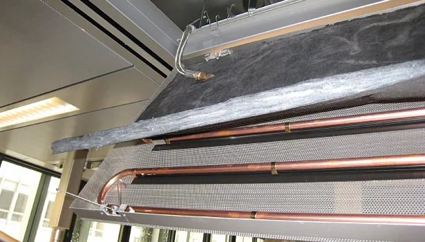 Close-up of radiant ceiling panel components: metallic ceiling panel, coil, thermal insulation and stainless steel flexible connectors.