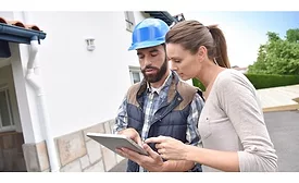 Man in hard hat looking at ipad with woman