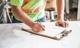 Construction worker writing on paper on top of table 5449651